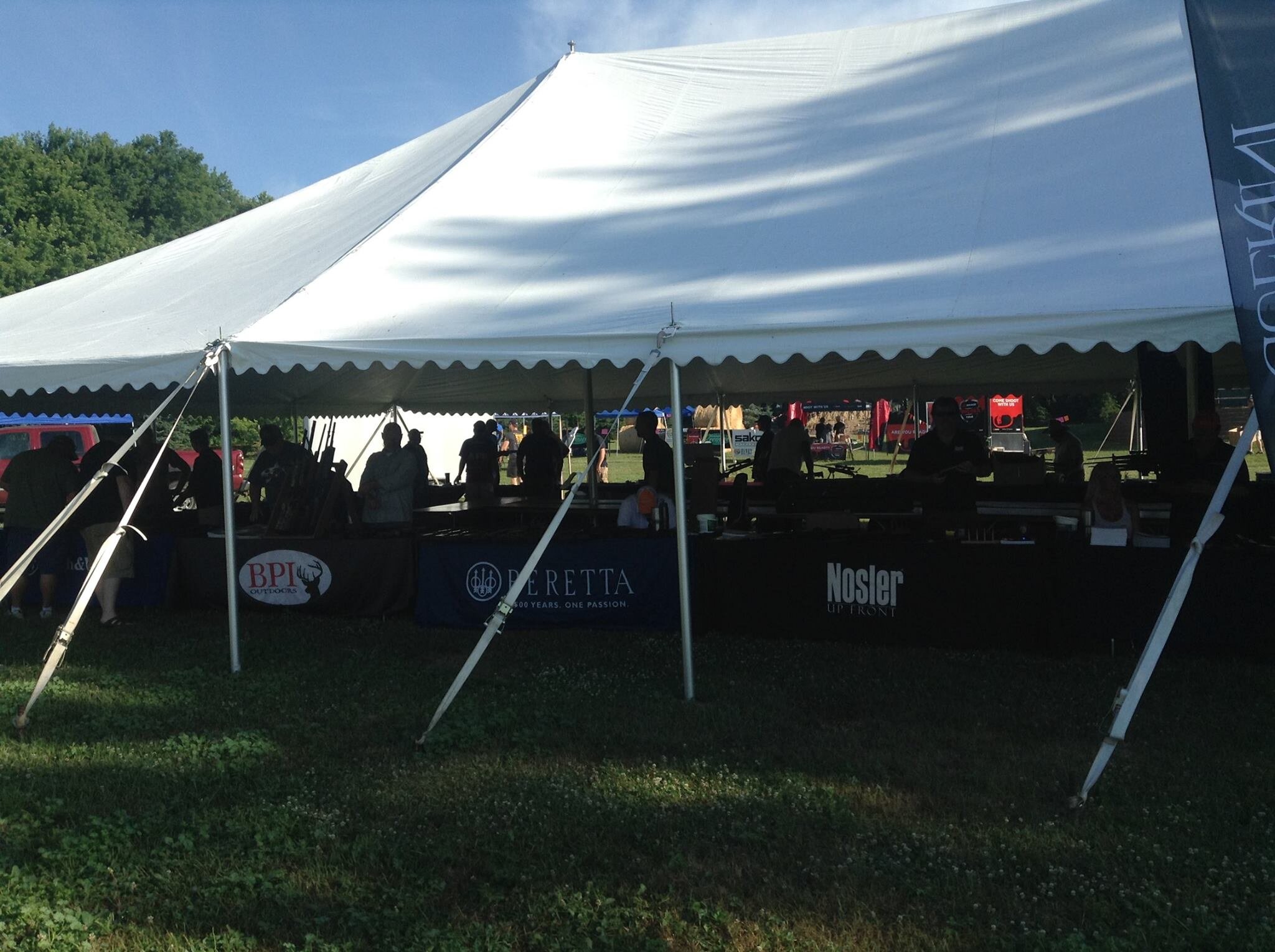 Customers browsing firearms inside a manufacturer event tent at Kjergaard Sports