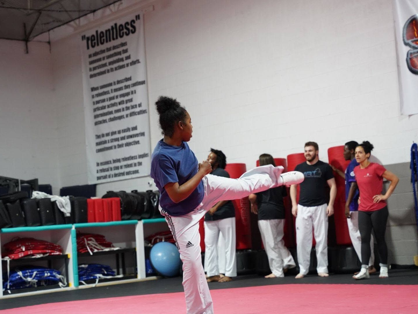 A Storm student demonstrating a controlled kick with adult classmates nearby