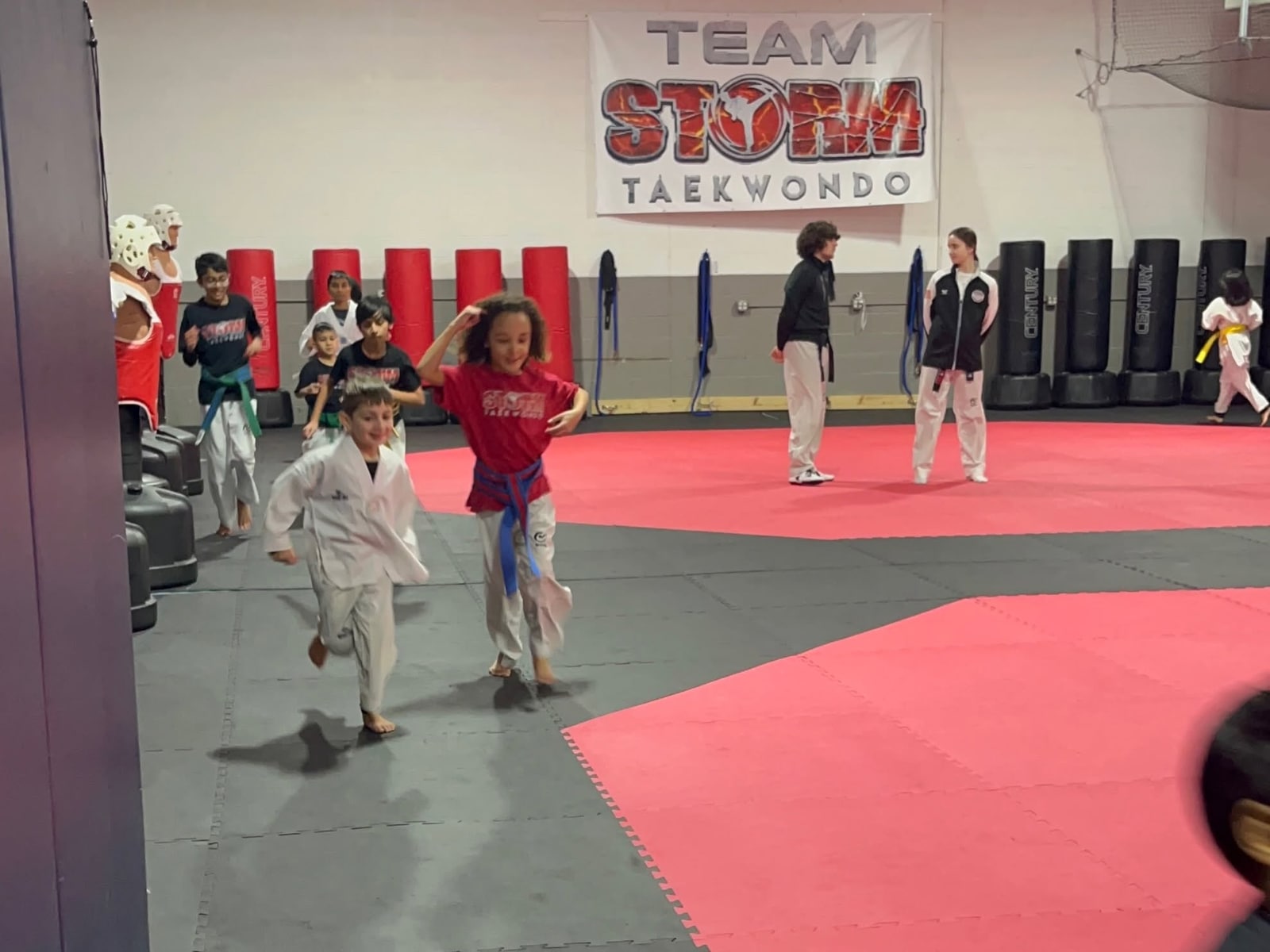 Younger Storm students running a warm-up drill while older students practice nearby