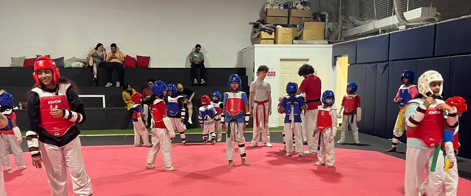 Students of different ages practicing in protective gear at Storm Taekwondo
